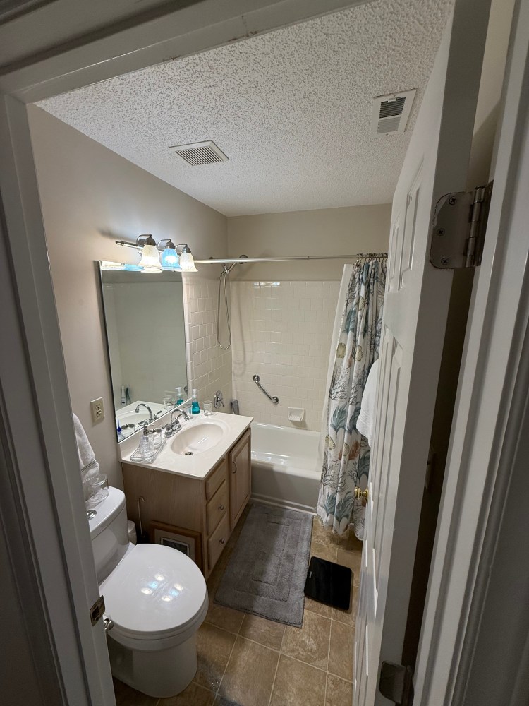 Full bathroom with tub, vanity and commode